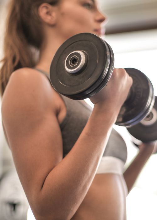 closeup of woman lifting weights with arms brown hair